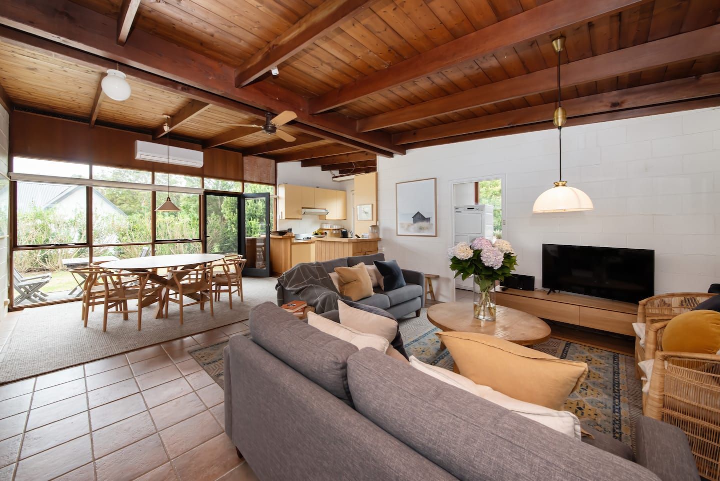The open living and dining room, lined in timber, with the deck beyond