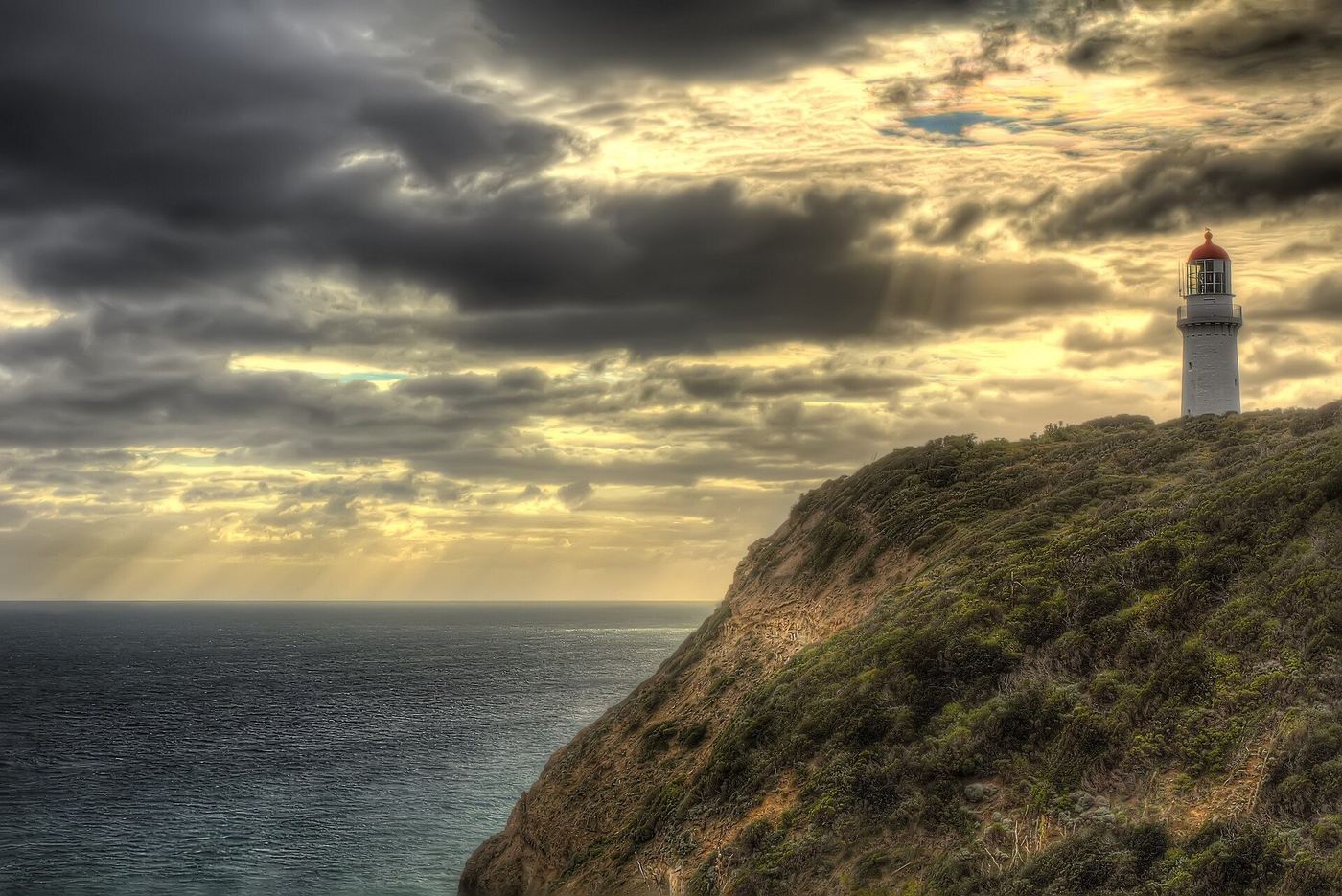 Cape Schanck lighthouse on its cliff under dramatic clouds and shafts of evening light, Mornington Peninsula