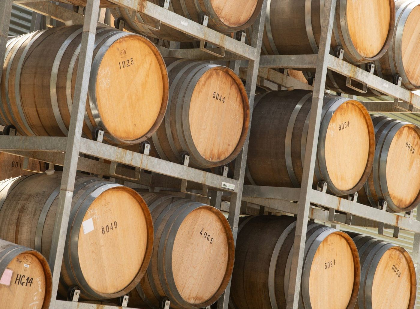 Oak wine barrels stacked on steel racks in a winery cellar at Merricks on the Mornington Peninsula
