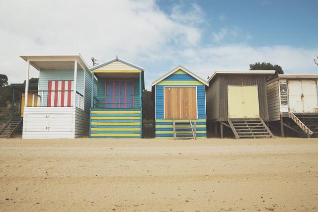 Row of colourful striped bathing boxes on the sand at Mornington Beach, Mornington Peninsula